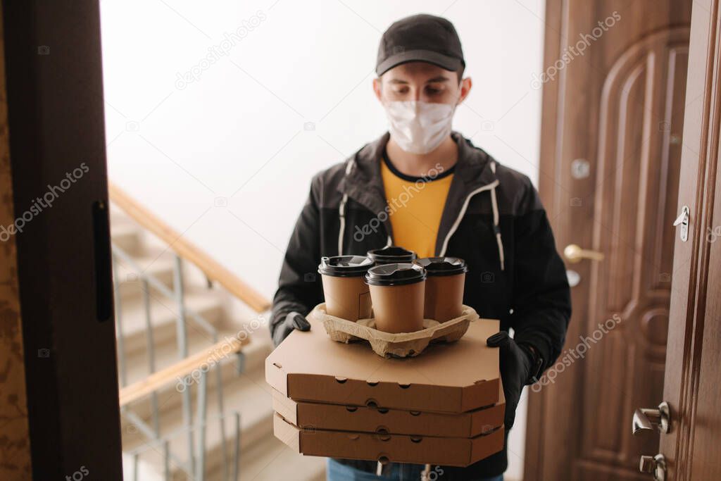 First persom view of delivery man in mask and gloves give pizza and coffe. Stay home