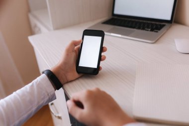 Öğrenci çocuk odasında, masasında ders çalışıyor. Çocuk deftere yazmak için dizüstü bilgisayar ve akıllı telefon kullanıyor. Kitaplar ve tablet masanın üstünde. Qurantine sırasında evde çalış. Model