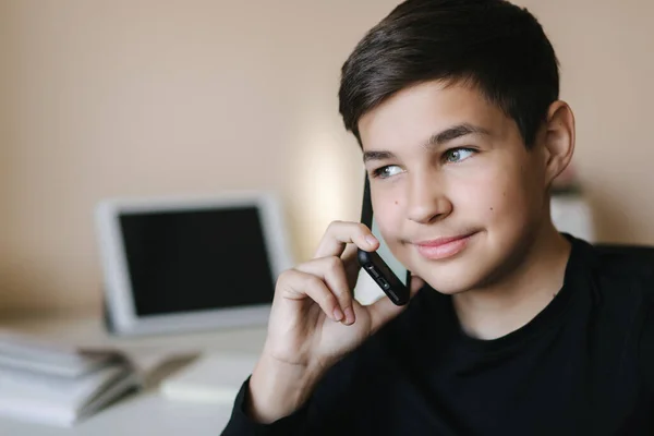 Retrato do jovem adolescente em casa falando por telefone. Antecedentes de tablet e livros — Fotografia de Stock