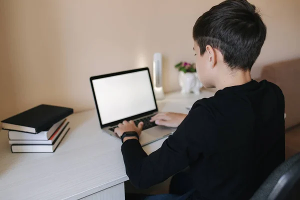Мальчик-подросток сидит дома на верхушке пальца. Мальчик играет в онлайн игры дома. Обучение в карантине. Счастливый школьник во время квантина — стоковое фото
