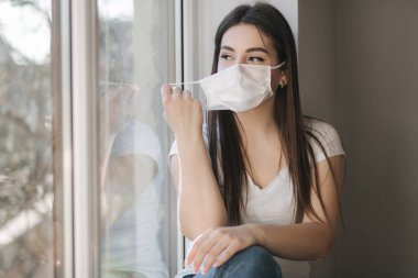 Genç kadın koruyucu maskeni çıkar ve akıllı telefon kullan. Karantina sona erdi. Coronavirus teması