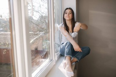 Genç bir kadın koruyucu maskesini çıkarıp dışarı atıyor. Beyaz tişörtlü ve beyaz tıbbi maskeli bir kadın. Karantina sona erdi. Coronavirus teması