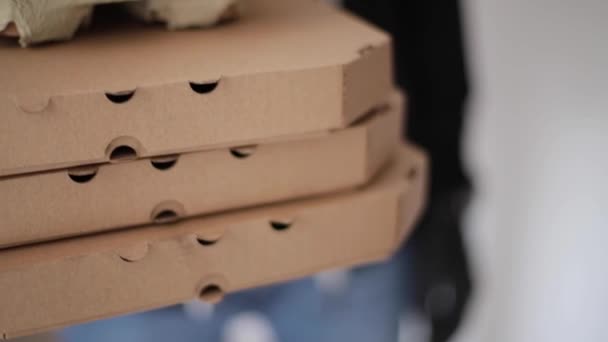 Chiudere l'uomo tenere scatole di alberi di pizza. Uomo consegna cibo e caffè al cliente in maschera e guanti. Tema Coronavirus — Video Stock