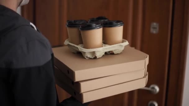 Close-up van de mens houden boomkisten met pizza. Man levering van voedsel en koffie aan de klant in masker en handschoenen. Coronavirus thema — Stockvideo
