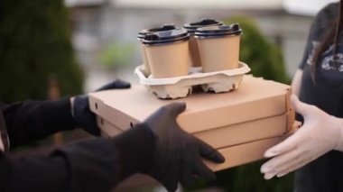 Kurye kapanışı, müşteriye sipariş verin. Teslimat servisinden bir adam pizza ve kahve getirdi. Eller koruyucu maskeli