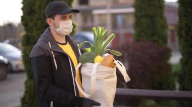 Koruyucu maskeli ve tıbbi eldivenli kurye bayan müşterilere taze yiyecek getiriyor. Teslimat servisi karantina altında. Coronavirus covid-19 teması