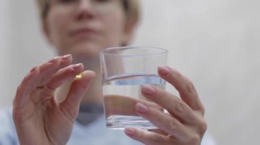 Kadın hap alıyor ve bir bardak su tutuyor. Karantinada olan bir kadın. Kendini soyutlama. Helthy kadın vitamin alıyor.