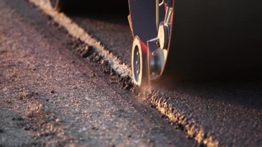 Yeni yapılmış düz bir yolda kaldırım taşıma aracı, çarpıyor ve düzleştiriyor. Asfalt kaldıracı tamir edilen şehir yoluna asfalt uyguluyor