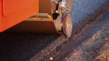 Yeni yapılmış düz bir yolda kaldırım taşıma aracı, çarpıyor ve düzleştiriyor. Asfalt kaldıracı tamir edilen şehir yoluna asfalt uyguluyor