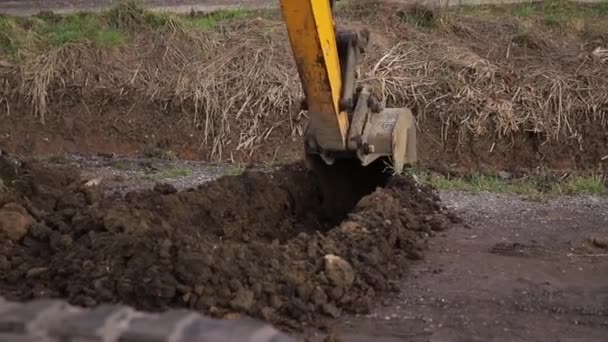 掘削機は土杭の上ですくって投棄します。クレーン上のトングは、建設材料を運ぶ。物質が少ない。森林の背景 — ストック動画