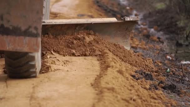 Grävmaskinen rätar ut kanterna på vägen och skiftar jord. Förberedelser för arbetet. Plats för gränsen — Stockvideo