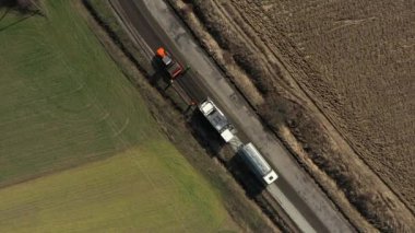 Kamyonun hava manzarası yola kumu döküyor.