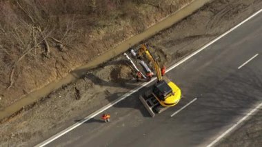 Kazıcı 'nın toprak yığınına atlama ve boşaltma görüntüsü. Vinçteki maşalar inşaat malzemeleri taşır.