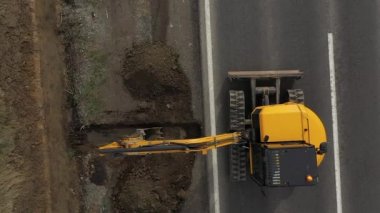 Kazıcı 'nın toprak yığınına atlama ve boşaltma görüntüsü. Vinçteki maşalar inşaat malzemeleri taşır.
