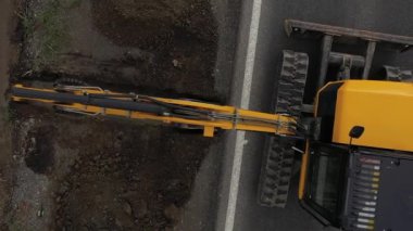 Kazıcı 'nın toprak yığınına atlama ve boşaltma görüntüsü. Vinçteki maşalar inşaat malzemeleri taşır.