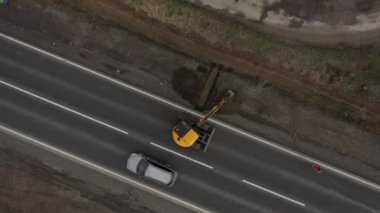 Kazıcı 'nın toprak yığınına atlama ve boşaltma görüntüsü. Vinçteki maşalar inşaat malzemeleri taşır.