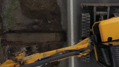 Kazıcı 'nın toprak yığınına atlama ve boşaltma görüntüsü. Vinçteki maşalar inşaat malzemeleri taşır.