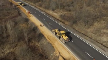 Farklı makinelerin insansız hava aracı görüntüleri yolu inşa ediyor. Kazıcı, minibüs, kamyon.