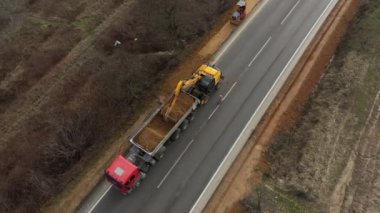 Farklı makinelerin insansız hava aracı görüntüleri yolu inşa ediyor. Kazıcı, minibüs, kamyon.
