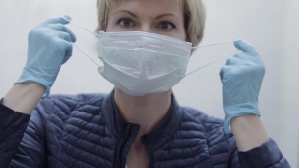 Frauen ziehen Schutzmaske an. Allein zu Hause in Quarantäne. Coronavirus Thema. Zu Hause bleiben — Stockvideo