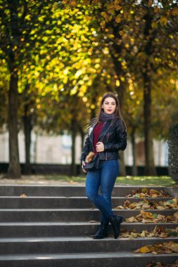 Siyah çantalı, siyah deri ceketli şık bir bayan. Çekici genç kadın gülümsemesi.