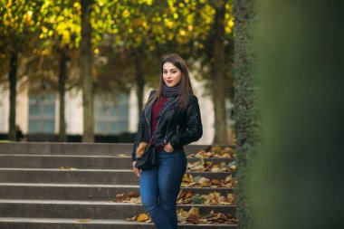 Siyah çantalı ve bordo bluzlu siyah ceketli şık bir bayan.