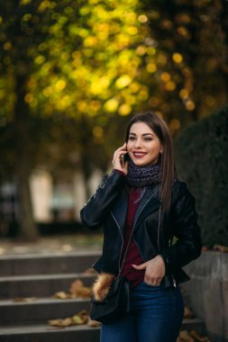 Siyah çantalı ve bordo bluzlu siyah ceketli şık bir bayan. Çekici genç bayan telefonda konuşuyor.