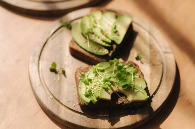 Ahşap boadr üzerinde avokado tostu. Vejetaryen gıda konsepti. Evde taze yemek. Avokado ve çavdar ekmekli sandviç, susam tohumu ve hardal tohumu.