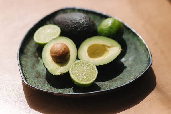 Mitades de aguacate y lima en plato verde. Concepto de comida vegetariana —  Fotos de Stock