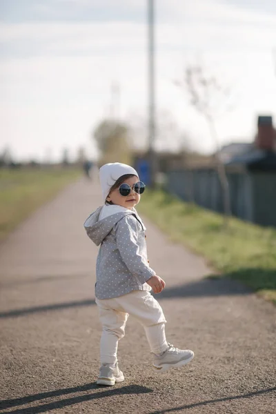 Schattig meisje dat in het park bij de dijk loopt. Stijlvol baby meisje in zonnebril — Stockfoto