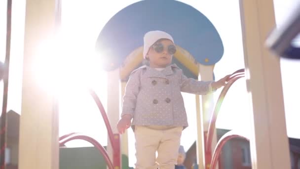 Carino passeggiata bambina nel parco giochi e buon divertimento. Adorabile ragazza in abiti eleganti — Video Stock