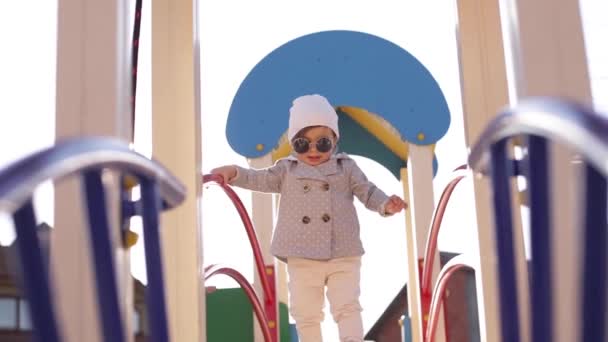 Carino passeggiata bambina nel parco giochi e buon divertimento. Adorabile ragazza in abiti eleganti — Video Stock