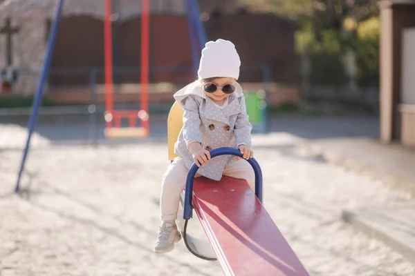 Schattig klein meisje lopen in de speeltuin en veel plezier. Schattig meisje in stijlvolle kleren — Stockfoto