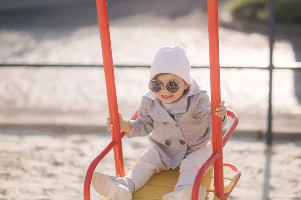 Schattig meisje op de schommel in de speeltuin. Gelukkig meisje, veel plezier. Een en romp jaar meisje — Stockfoto