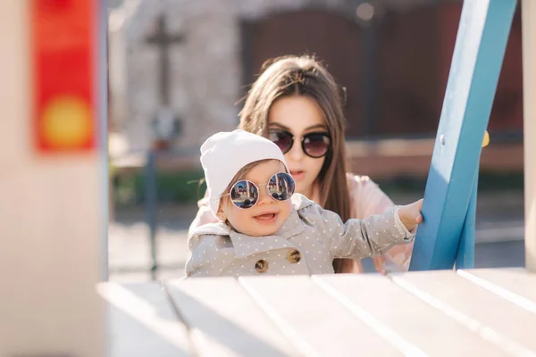 Adorable little girl play with her mom in the playground. Mom and daughter spend time together in Mothers Day. Happy family — Stock Photo, Image