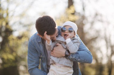 Babasının elinde mutlu şirin bir kız. Baba ve kızı parkta yürüyor. Aile havası. Biraz gül.