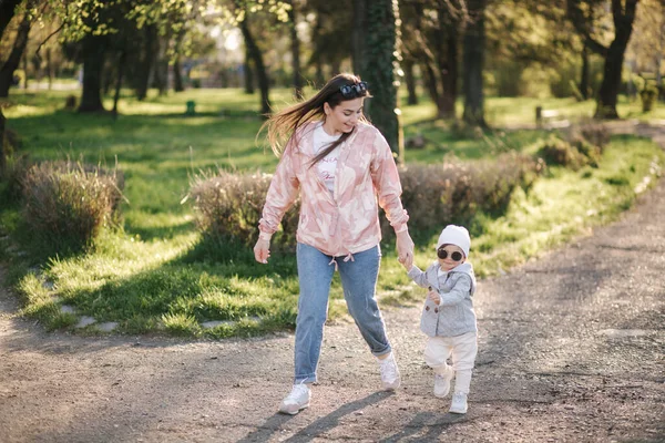 Krásná máma s rozkošnou dcerou procházka v parku. Šťastná rodina tráví čas na Den matek. Roztomilá holčička s matkou. Stylový ženský běh a bavte se — Stock fotografie