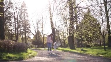 Güzel bir anne ve güzel kızı parkta yürüyor. Mutlu aile anneler gününde vakit geçirir. Annesiyle küçük tatlı bir kız. Şık kadın koş ve eğlen.