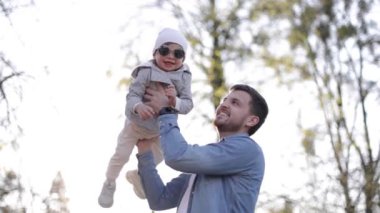 Küçük sevimli Gilr babasıyla vakit geçiriyor. Baba ve kızı parkta yürüyor. Şık bir aile. Güneş gözlüklü mutlu küçük kız