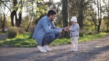 Küçük sevimli Gilr babasıyla vakit geçiriyor. Baba ve kızı parkta yürüyor. Şık bir aile. Güneş gözlüklü mutlu küçük kız. Baba, kızına biraz taş ver.