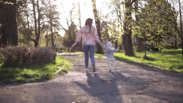 Beautiful mom with adorable daughter walk in the park. Happy family spend time in Mothers Day. Cute little girl with mother. Stylish female run and have fun — Stock Video