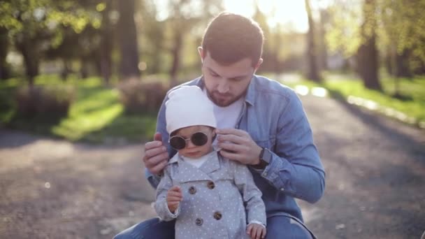 Папа надел солнцезащитные очки для своей маленькой дочери в сууни-день — стоковое видео