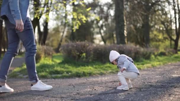 La adorable pequeña Gilr pasa tiempo con su padre. Papá y su hija caminan por el parque. Una familia con estilo. Niña feliz con gafas de sol. Papá le da algunas piedras a su hija — Vídeos de Stock