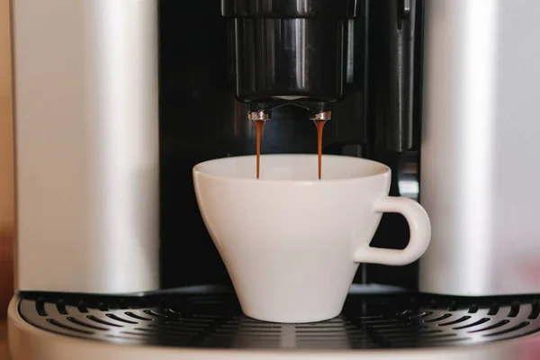 Primer plano del café expreso que se vierte de la máquina de café en casa. Taza blanca para Americano —  Fotos de Stock
