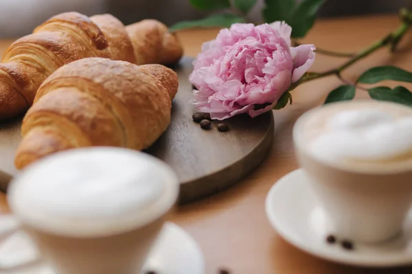 Vegan breakfast at home. Cappuccino with coconut milk and two empty vegan croissants. Morning with coffe. Pink peony flower on table