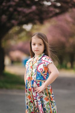 Genç kız manken fotoğrafçıya poz veriyor. Bayan çocuk. Dışarıda güzel elbiseler var.