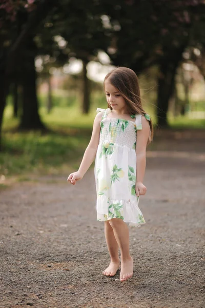 귀여운 소녀는 맨 발로 밖으로 걸어 나온다. 신선 한 공기 가 공원에 있어. 격리의 끝 — 스톡 사진