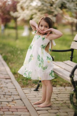 Mutlu bayan çocuk parkta bankta oturuyor. Güzel bir yaz elbisesi. Temiz hava. Karantinanın sonu