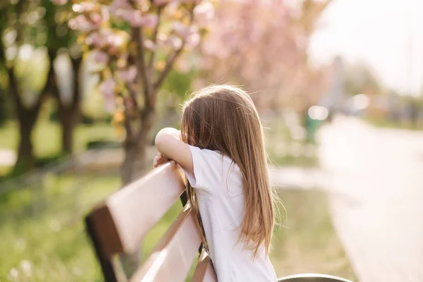 Happy female kid sits on the bench in the park. Fresh air. End of quarantine — Stock Photo, Image