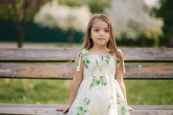 공원 벤치에 앉아 있는 행복 한 여자아이. 여름 드레스예쁘네요. 신선 한 공기. 격리의 끝 — 스톡 사진